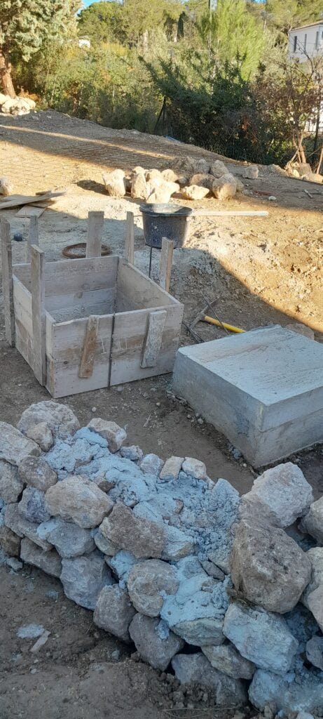 Coffrage bois d'un plot béton et pierres calcaires de récupération sur un terrain en cours de viabilisation