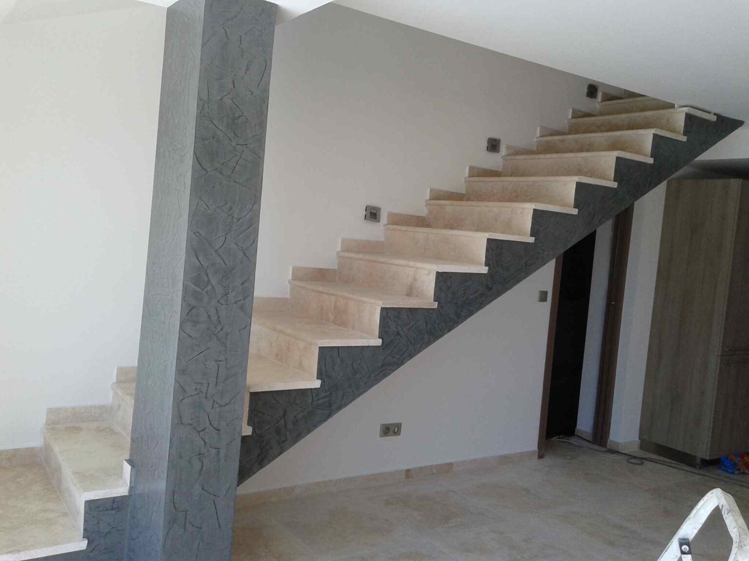 Escalier et sol habillés de pierre claire dans une maison rénovée