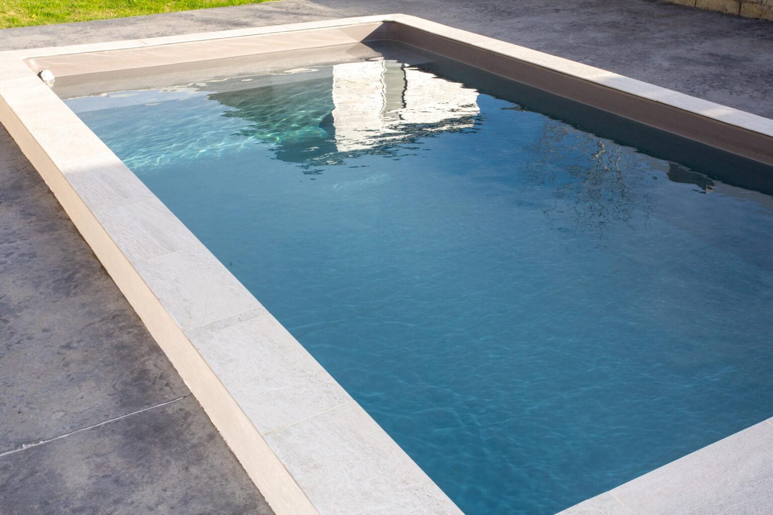 Plage de piscine en béton ciré gris bordée d'une margelle pierre naturelle, aménagement extérieur sur villa provençale