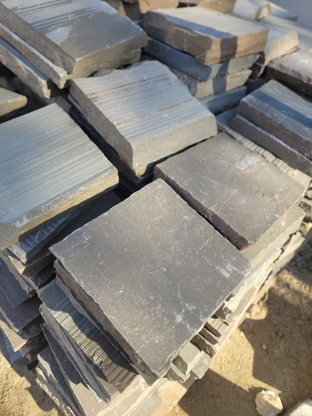 Lot de pavés ardoise empilés au sol — livraison chantier