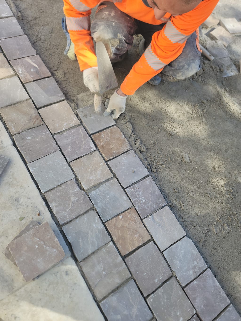 Maçon LMVP en train de poser un pavé calcaire — vue plongeante