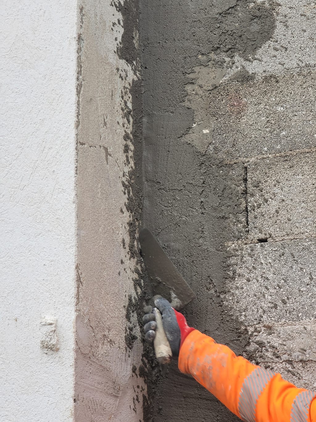 Lissage à la truelle de l'enduit en pied de mur — chantier mur soutènement Saint-Barnabé