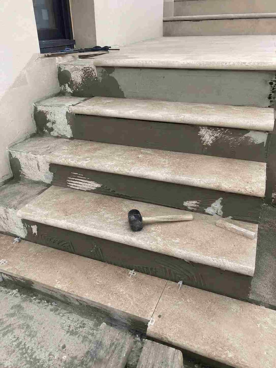 Pose de travertin sur les marches d'un escalier béton extérieur