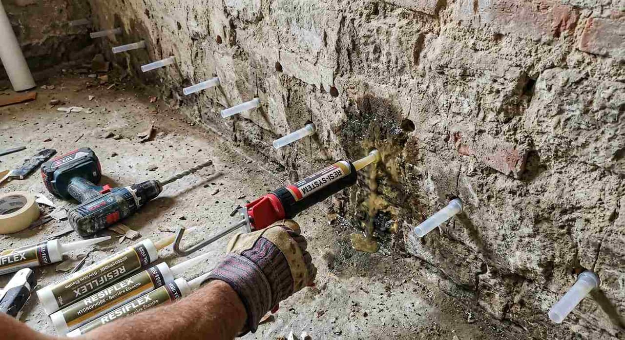 Injection de résine hydrophobe à la base d'un mur pour créer une barrière étanche contre les remontées capillaires