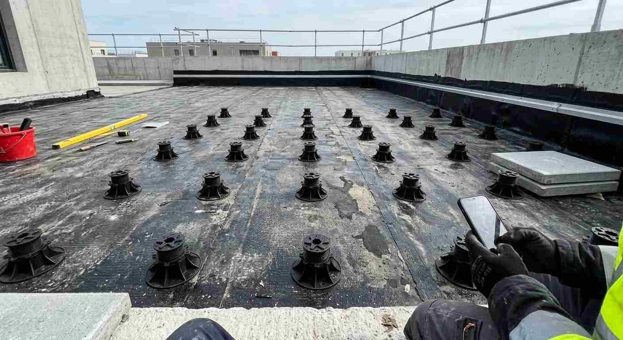 Plots réglables posés sur l'étanchéité d'un toit-terrasse avant pose des dalles