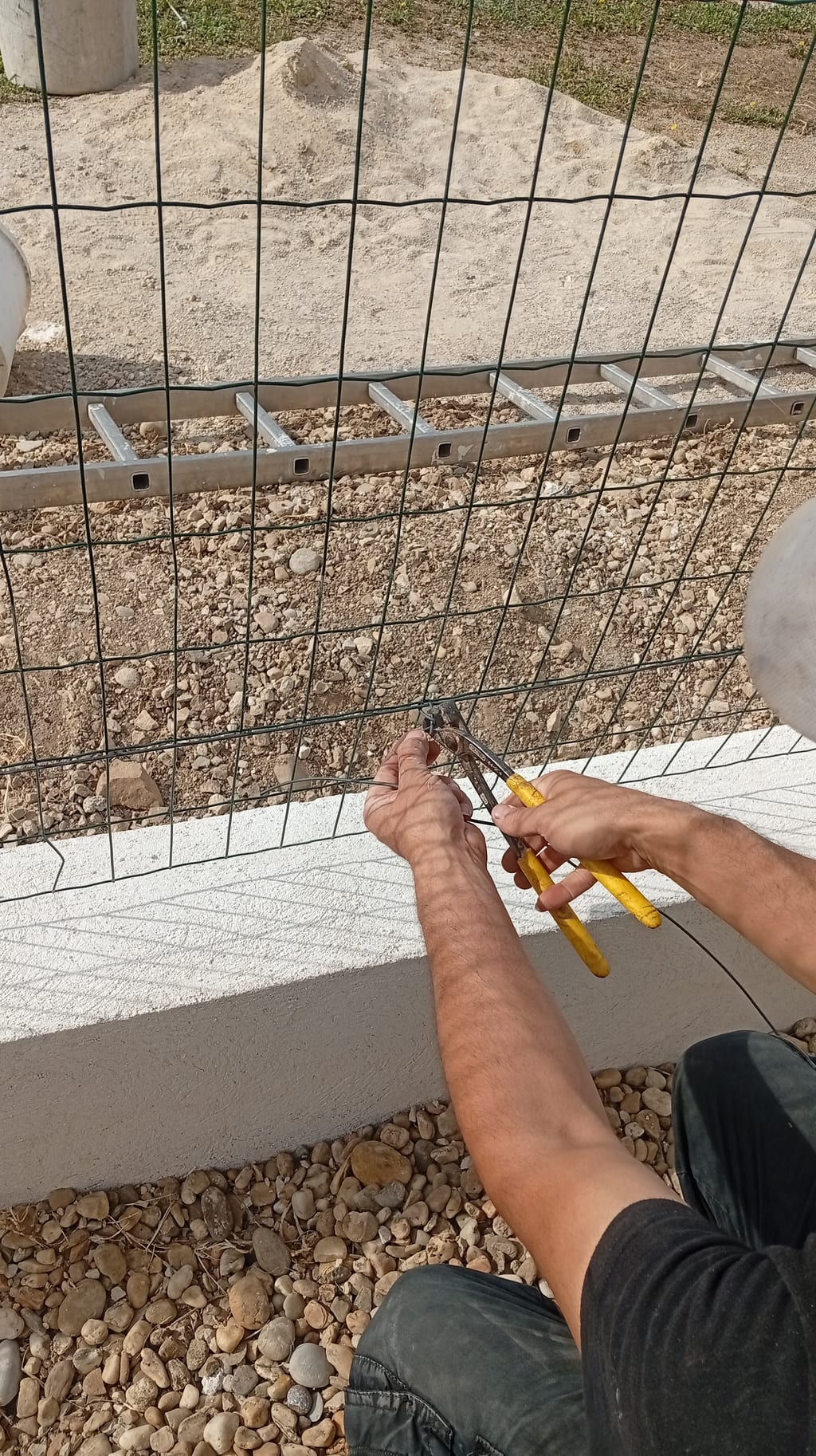 Ligature du grillage souple au-dessus de l'arase du muret en agglo à Miramas