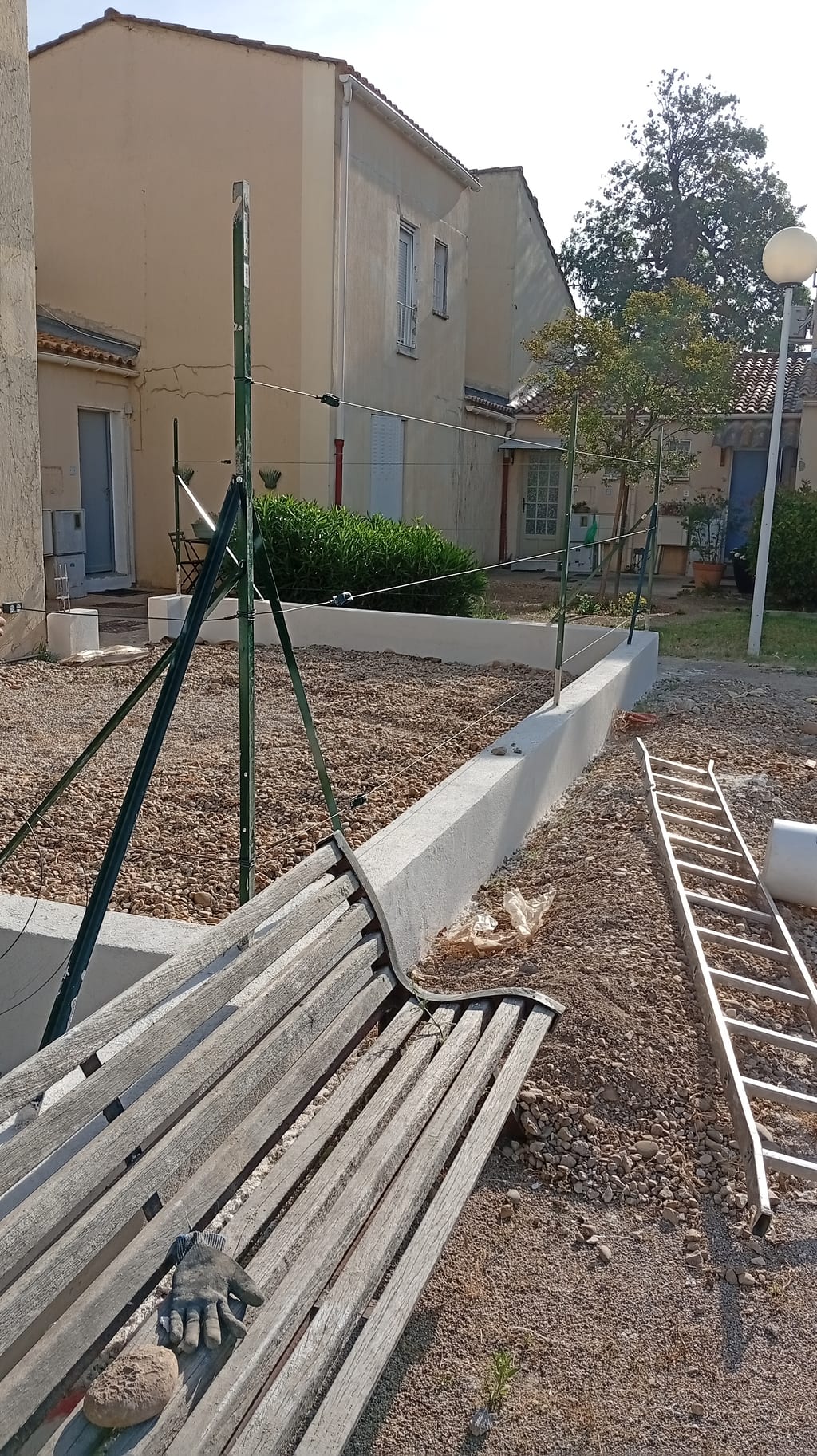Muret en agglo de 20 enduit ton pierre avec poteaux T50 verts et jambe de force à Miramas