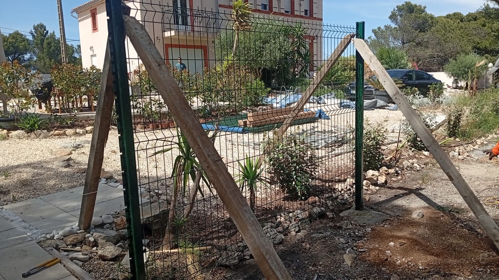 Travée de grillage rigide vert étayée par chevrons bois pendant la prise des scellements — Les Pennes-Mirabeau