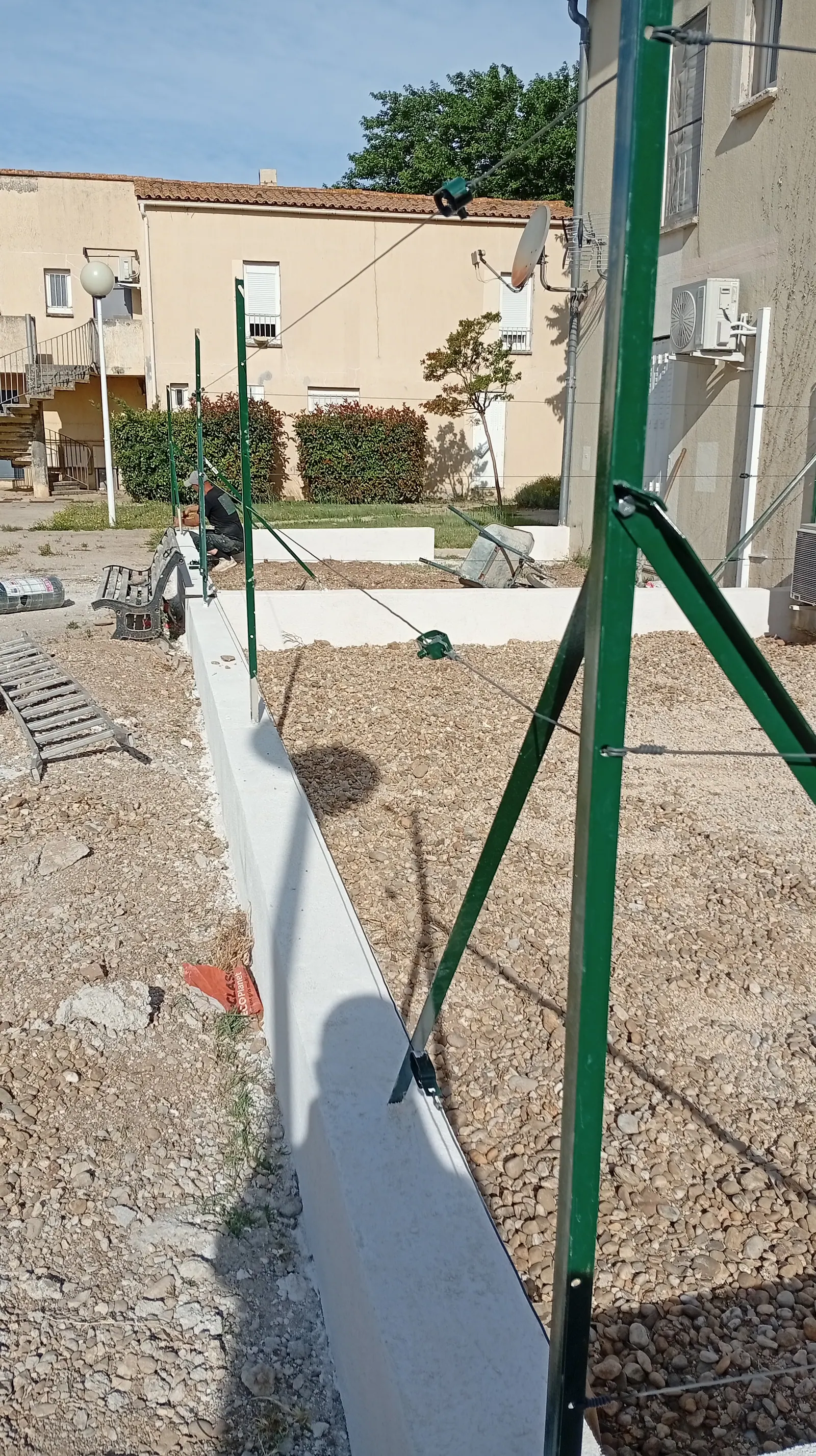 Poteau d'angle avec jambe de force scellé sur muret, renfort d'une clôture exposée au mistral en Provence