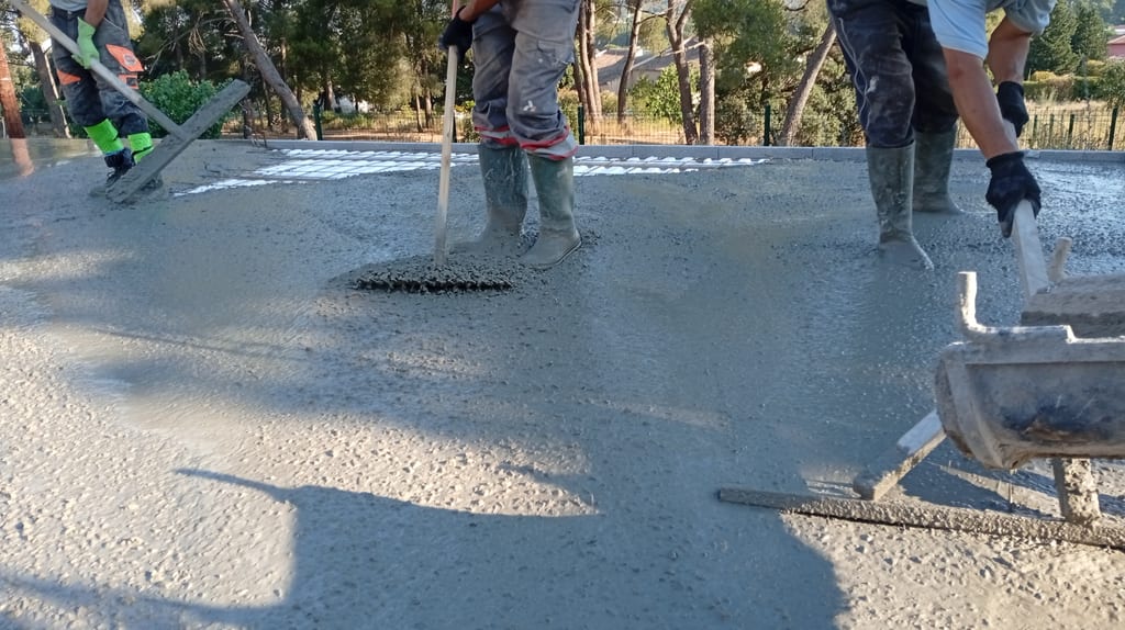 Étalement du béton frais au râteau pendant le coulage de la dalle de compression — chantier Aix-en-Provence, 9 juillet 2026