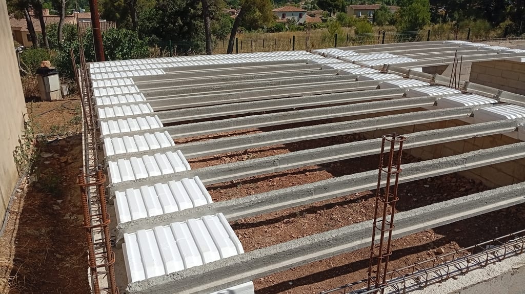 Pose des hourdis en polystyrène expansé entre les poutrelles précontraintes — chantier maison plain-pied Aix-en-Provence, juillet 2026