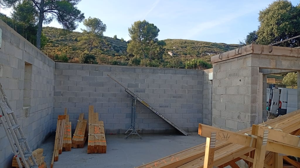Murs en agglo terminés et fermettes de charpente livrées sur la dalle d'une maison plain-pied à Aix-en-Provence